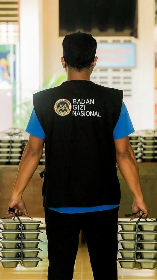 Petugas SPPG mengenakan rompi BGN membawa paket menu MBG
